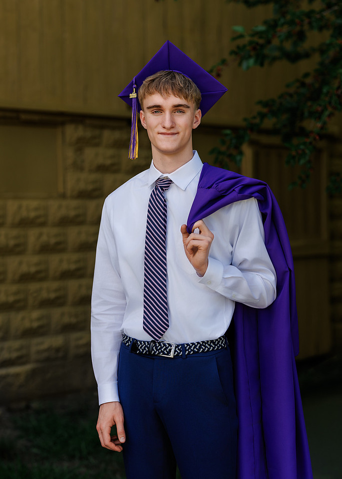 High school senior guy wearing a purple cap and gown for graduation portraits in Hamilton County, Indiana