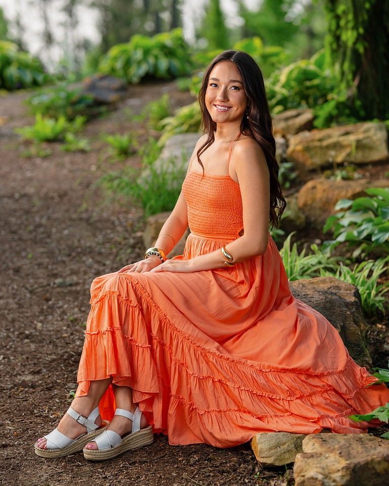 Senior girl in a coral dress surrounded by spring greenery in Hamilton County, Indiana